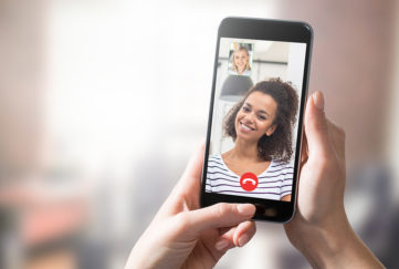 Smiling young woman on phone screen during video call, feature on how to make new friends