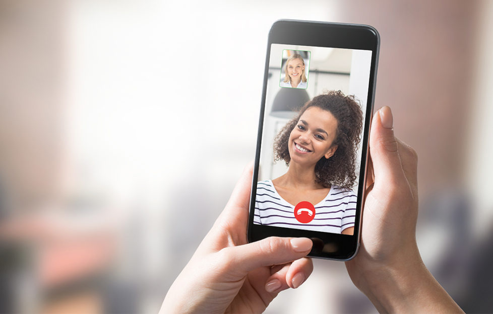 Smiling young woman on phone screen during video call, feature on how to make new friends