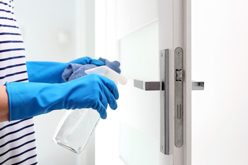 Cleaning the house, cleaning door handles. Prevention and prevention of infection. The woman cleans the apartment