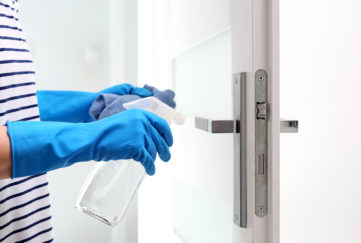Cleaning the house, cleaning door handles. Prevention and prevention of infection. The woman cleans the apartment