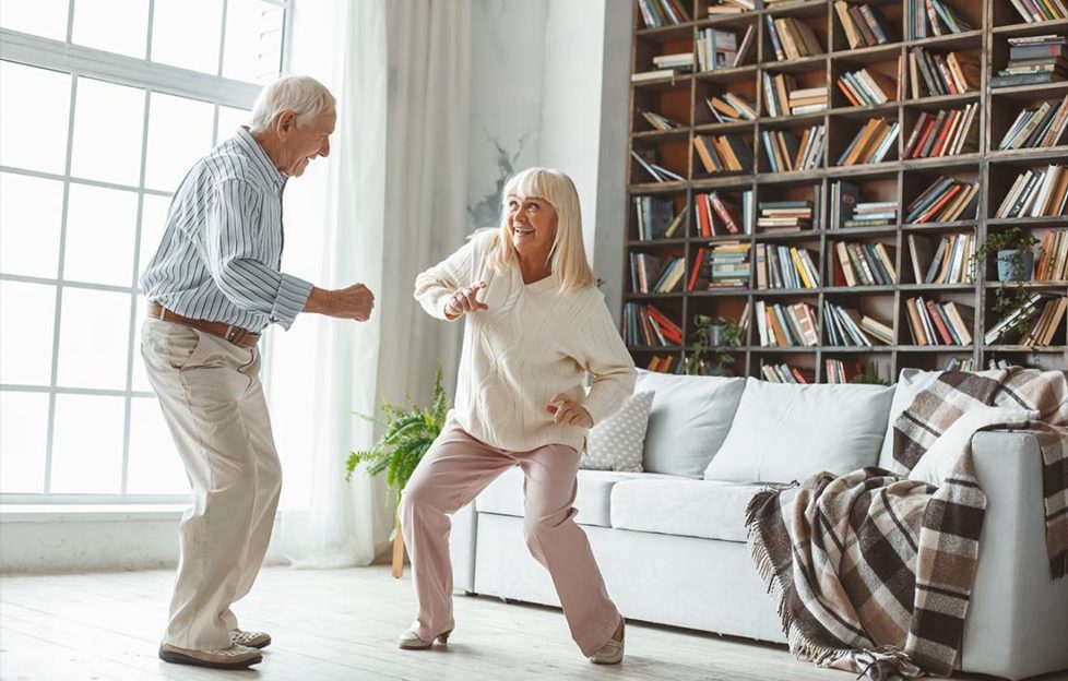 Senior couple together at home retirement concept dancing active dance playful