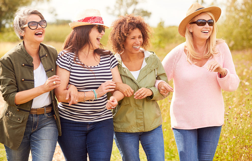 Group Of Mature Female Friends Walking Along Path Through Yurt Campsite