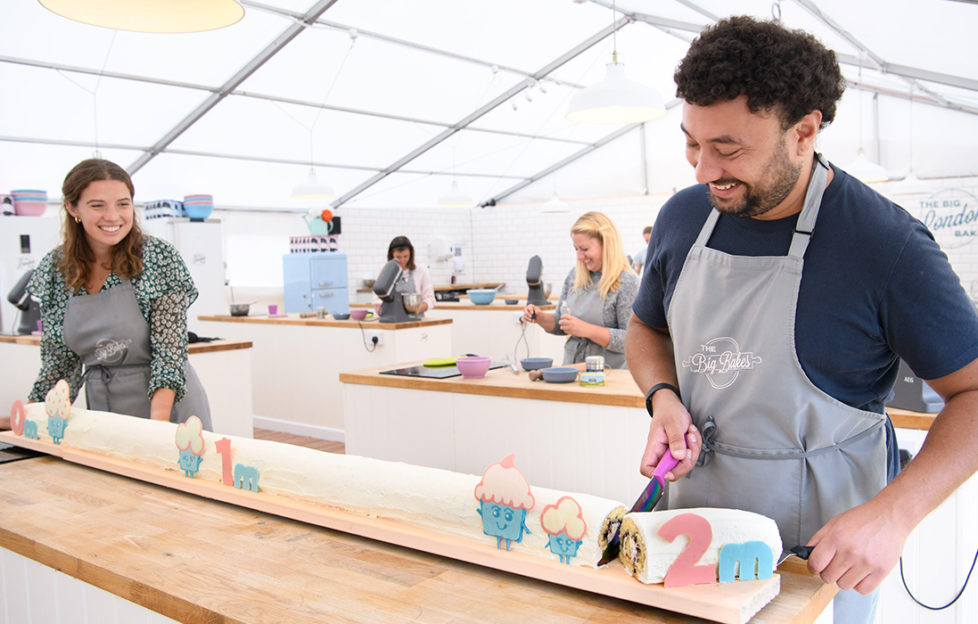 2 people in baking marquee cutting 2 metre long cake to show social distancing
