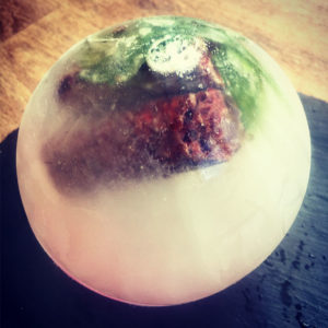 Ball of ice with dog treat and spinach leaves visible