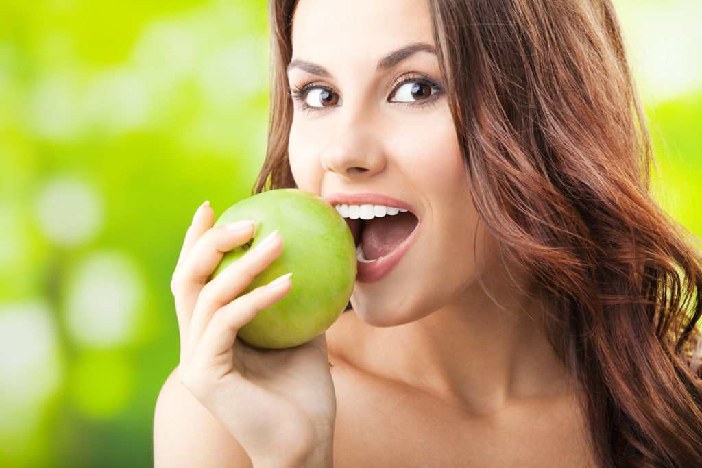 Young woman eating apple, outdoors; 