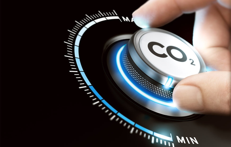 Man turning a carbon dioxide knob to reduce emissions. CO2 reduction or removal concept. Composite image between a hand photography and a 3D background.