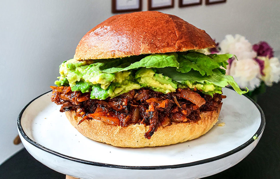 Large brioche roll filled with mashed avocado and savoury mushroom mixture