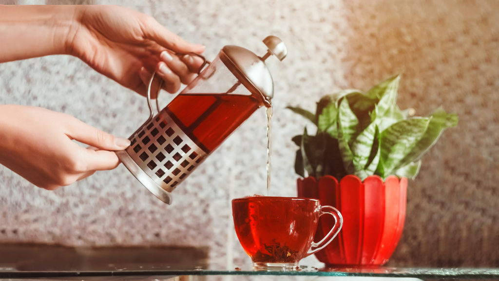 tea brewer. cup of hot tea. women's hands pour tea.; 