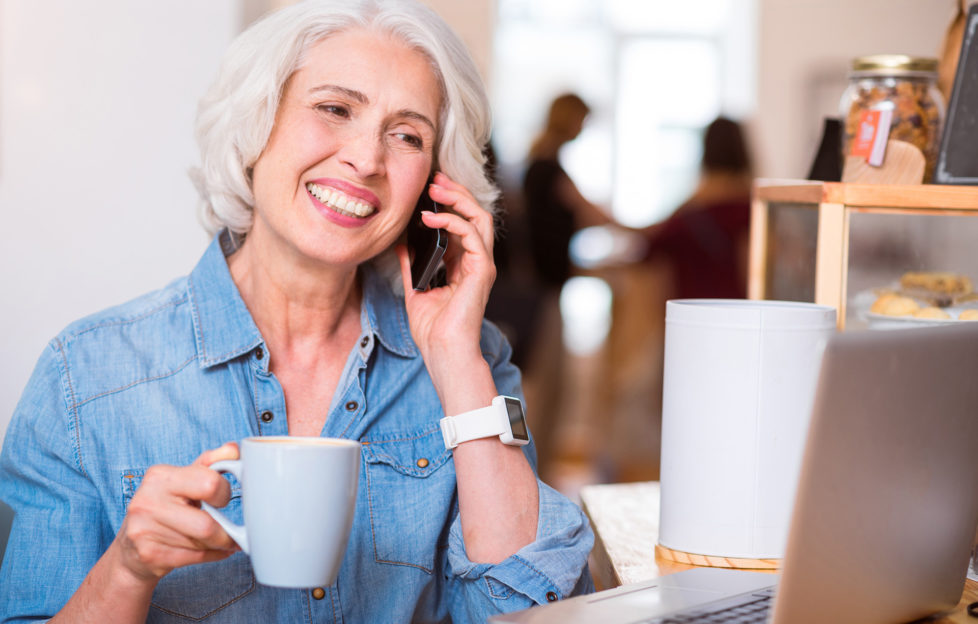 Older woman talking on mobile phone with cup of coffee