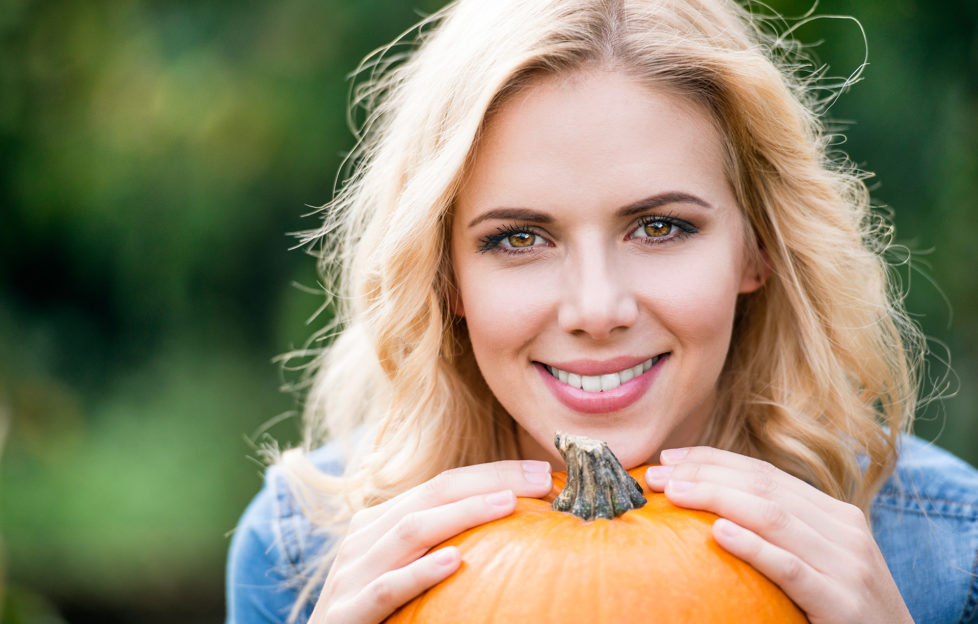 Close up, Beautiful young blond woman holding orange pumpkin;