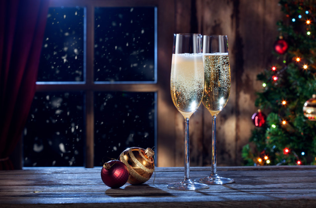 Two glasses of champagne beside Christmas baubles