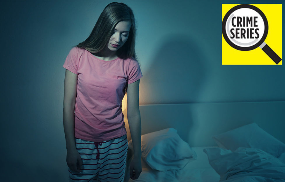 Young woman in pyjamas, eyes shut, gets out of bed in dark room