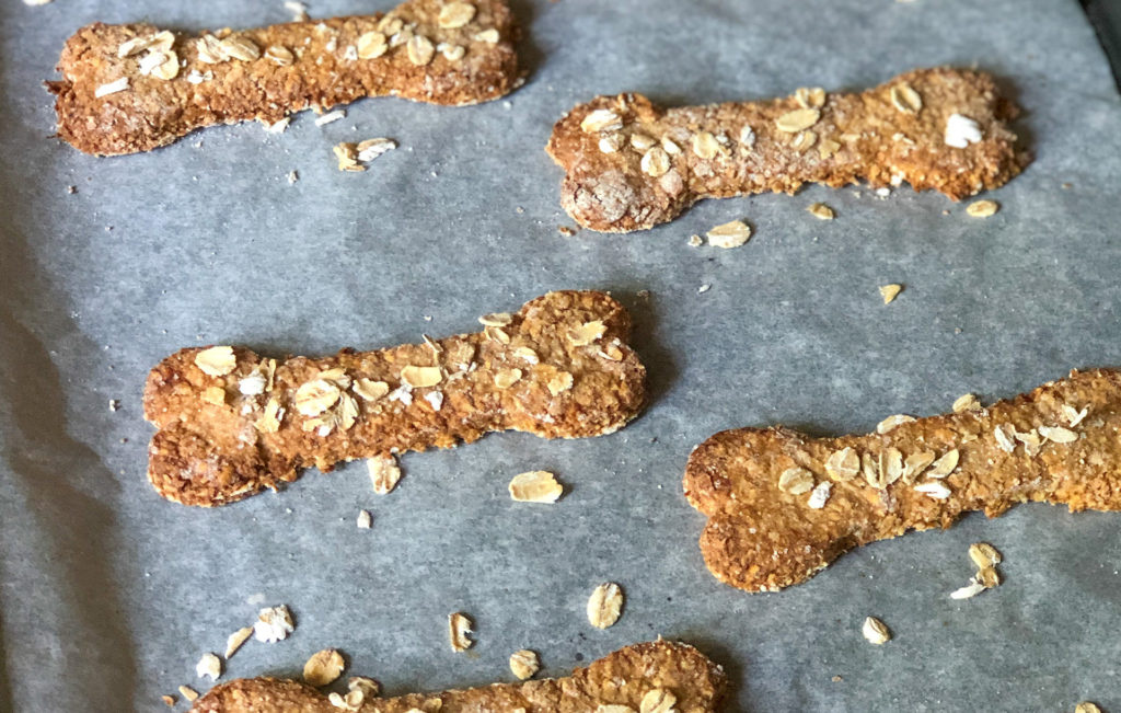 Oaty biscuits in shape of dog bones on a baking tray