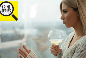 Elegant woman with glass of wine looks out of window