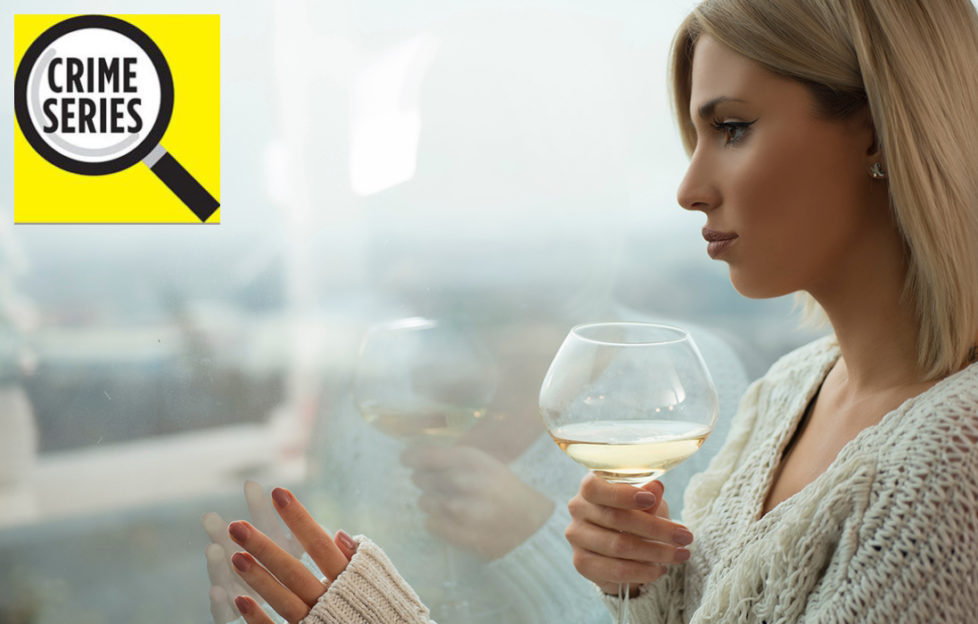 Elegant woman with glass of wine looks out of window