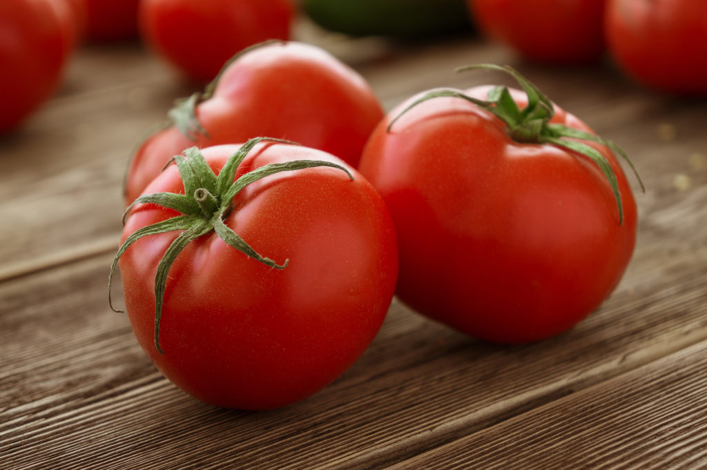 Close-up of fresh, ripe tomatoes on wood background; 