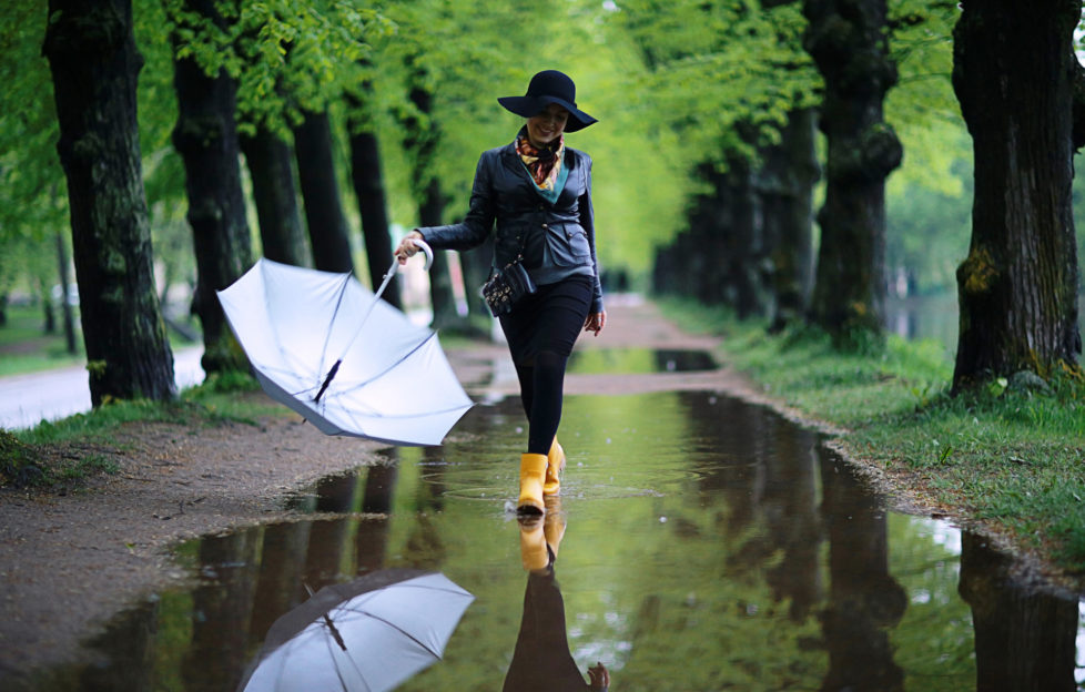 Woman in yellow wellies walking through puddles in park