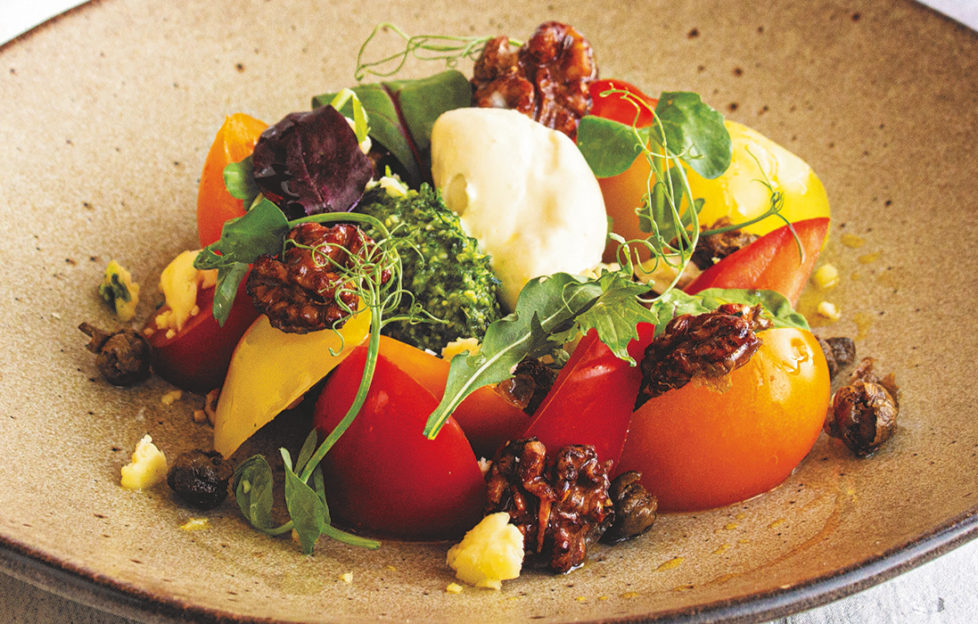 Colourful plate of salad with red and yellow tomatoes, green leaves and creamy white mousse