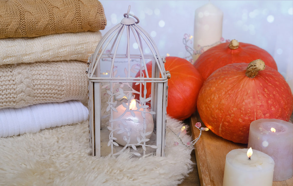 Folded blankets, sheepskin rug, candles and pumpkins, white decor