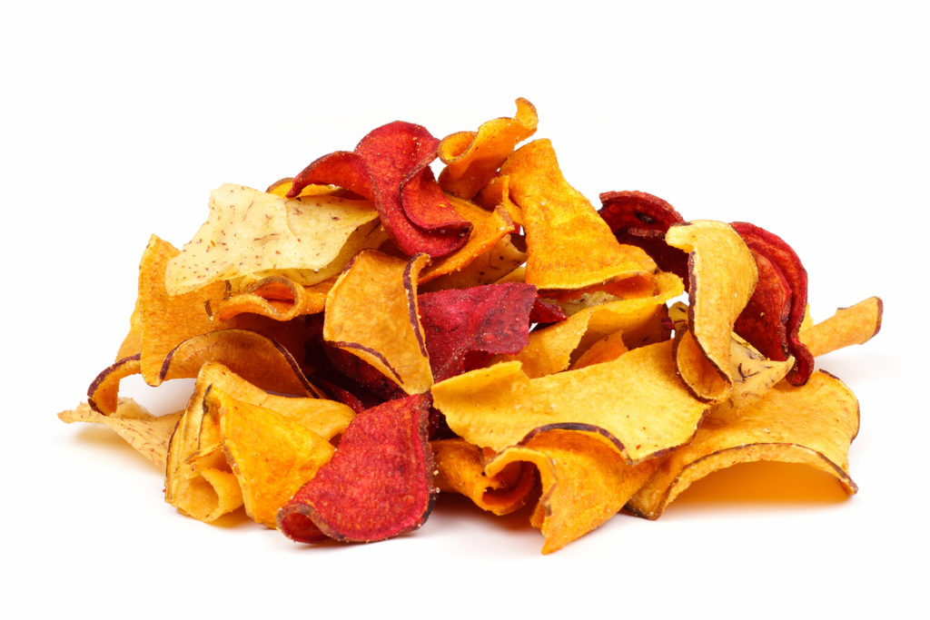 Pile of mixed healthy vegetable chips. Side view, isolated on a white background.