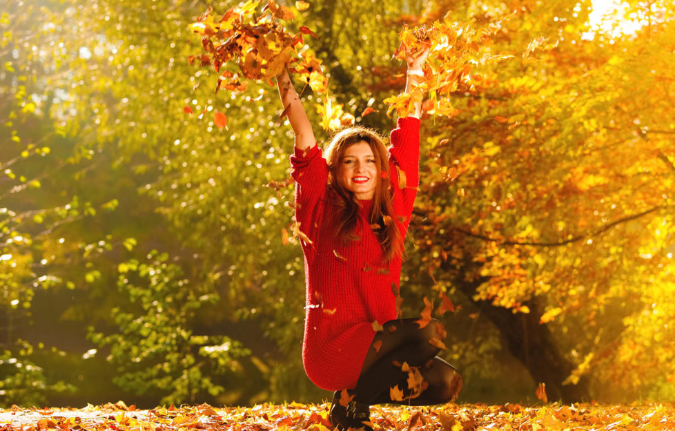 Happiness carefree. woman relaxing in autumn park throwing leaves up in the air with arms raised up. Beautiful girl in colorful forest foliage outdoor.;