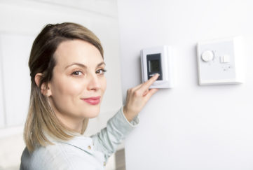 A woman set the thermostat at house.;
