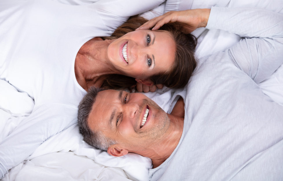 High Angle View Of Happy Mature Couple Lying On Bed;