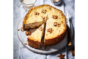 Baked cheesecake decorated with walnut halves, one slice cut