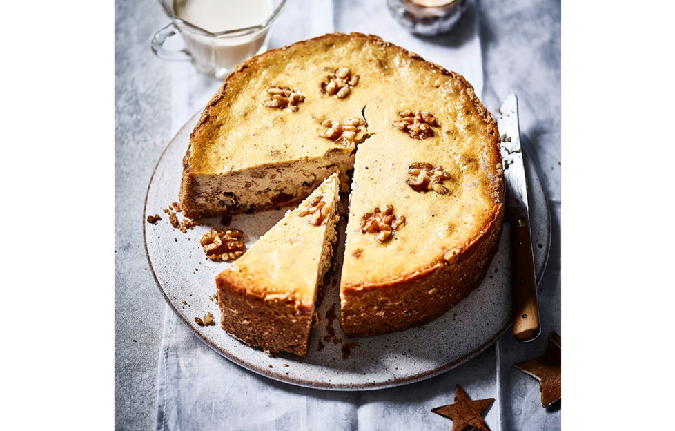 Baked cheesecake decorated with walnut halves, one slice cut