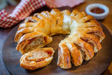sausage roll garland, ring of pastry with cuts, herby sausage filling showing through