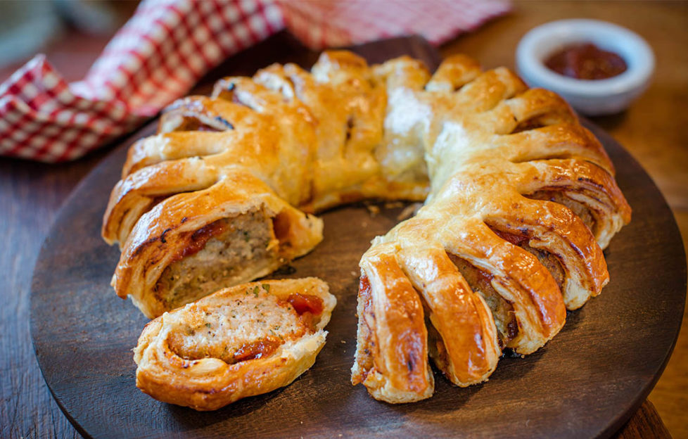 sausage roll garland, ring of pastry with cuts, herby sausage filling showing through