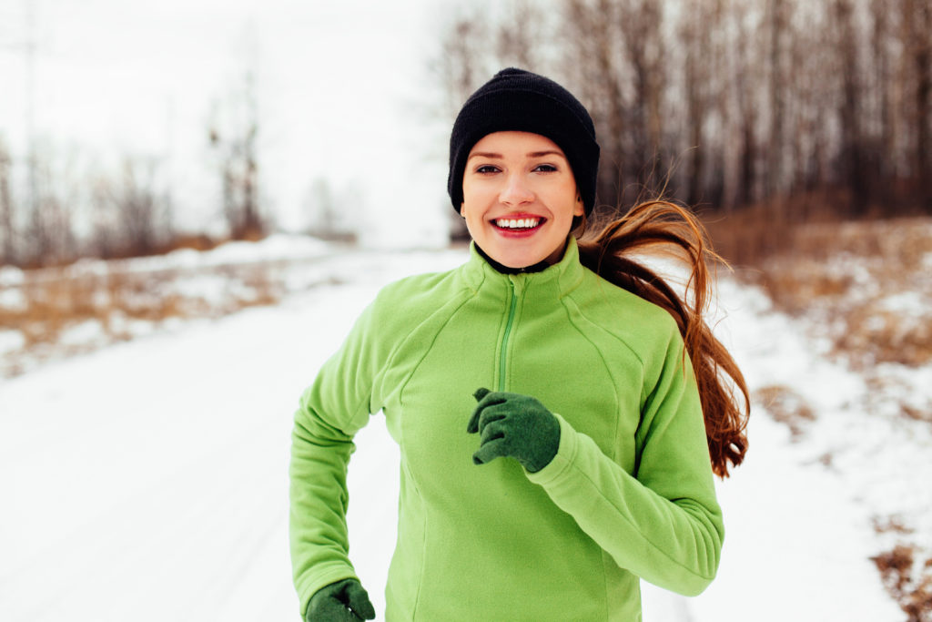 Happy young woman running in winter; 