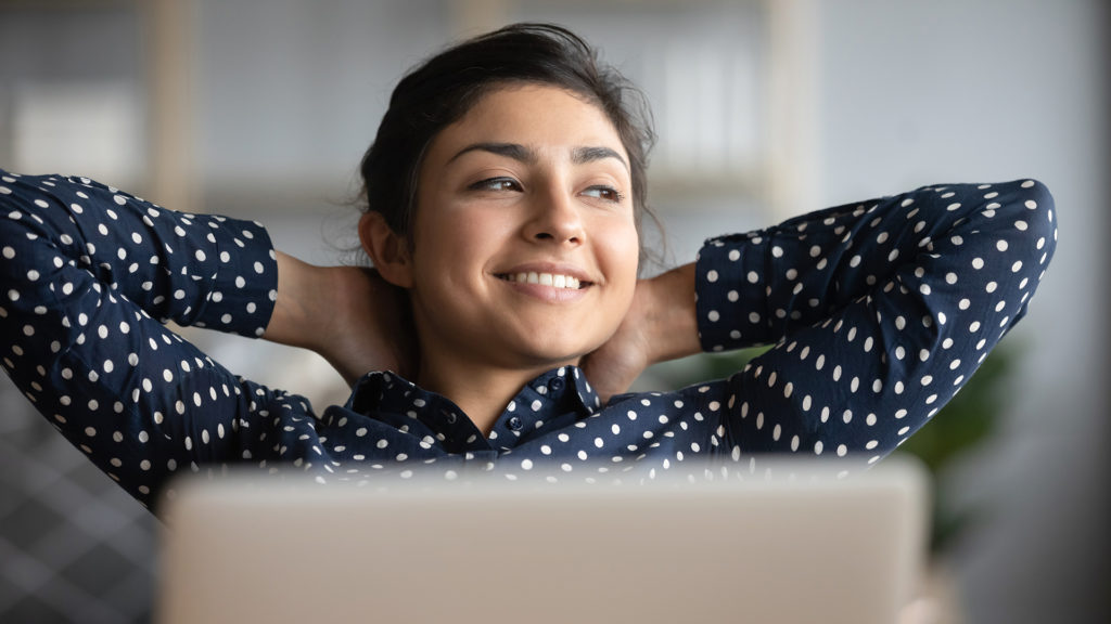 Happy satisfied indian woman rest at home office sit with laptop hold hands behind head, dreamy young lady relax finished work feel peace of mind look away dream think of future success concept; 