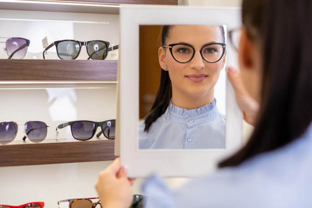 Young woman trying out glasses at an optician's shop; 