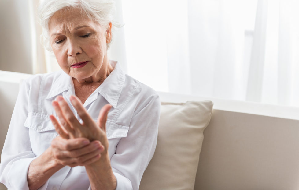Older woman rubs painful hand.
