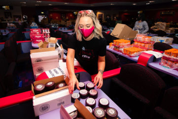 Woman in mask sorting goods for charity hampers