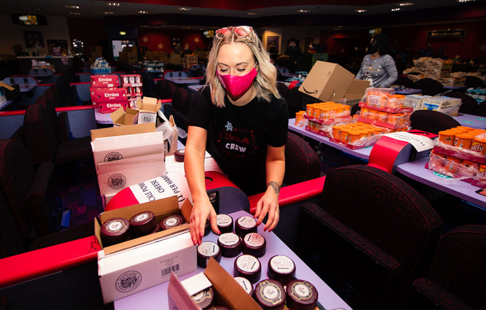 Woman in mask sorting goods for charity hampers