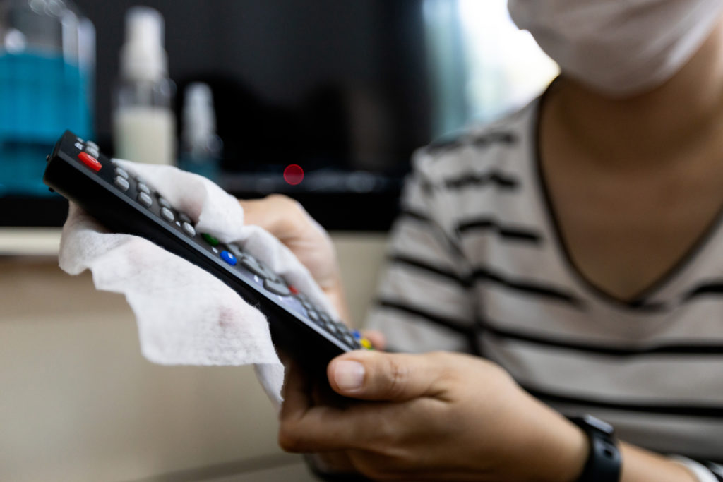 Woman using alcohol wet cloth,wipes the remote control of TV with disinfecting cloth,cleaning the things in a house with disinfectant,hygienic,prevention,during the pandemic of Coronavirus or Covid-19;