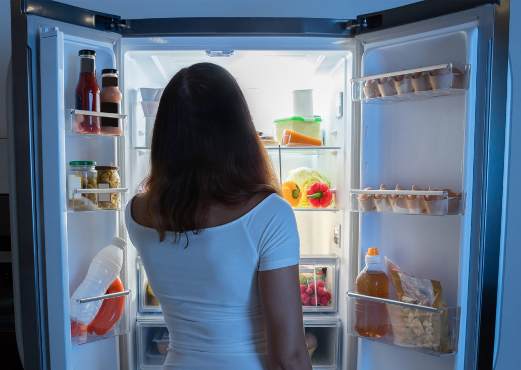 Rear View Of Young Woman Looking In Fridge