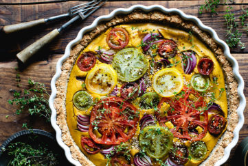 vegan quiche made with tofu and hazelnuts, topped with different coloured tomatoes and thyme sprigs