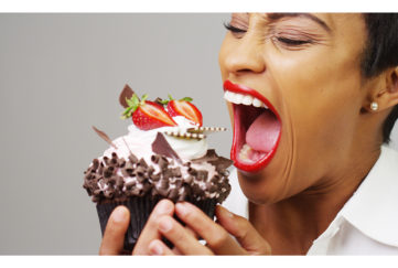 Black woman taking a huge bite out of a fancy dessert;