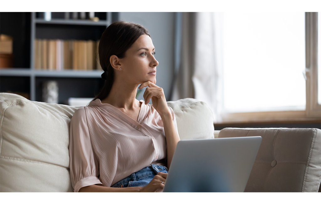 Woman staring past laptop in her living room