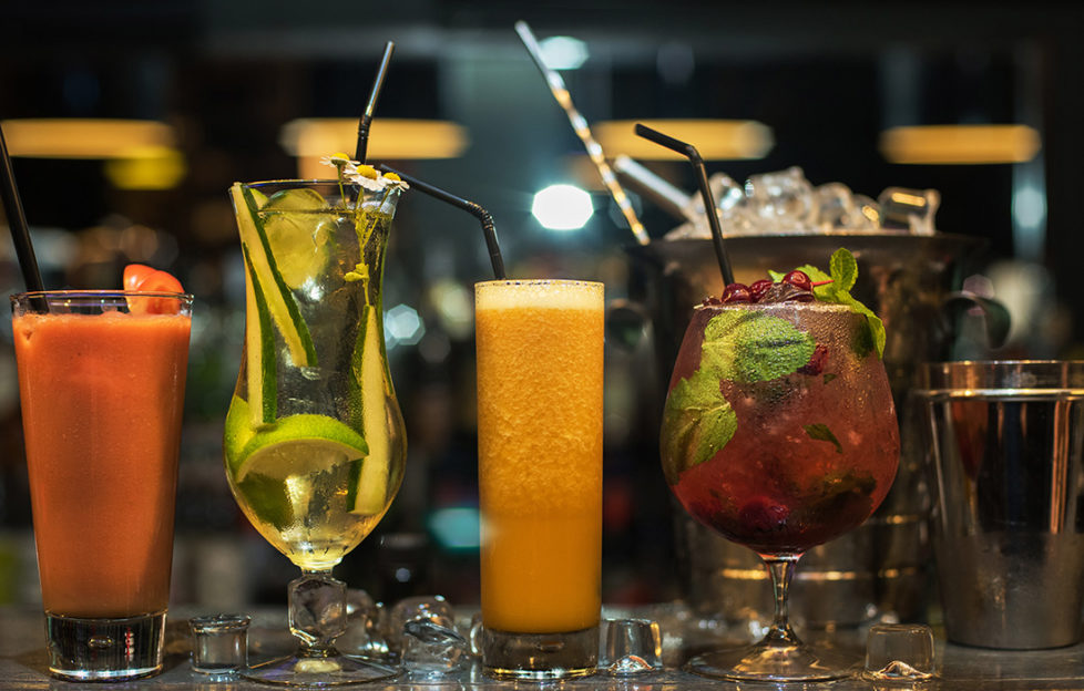 Glasses of different cocktails on bar background; World Cocktail Day