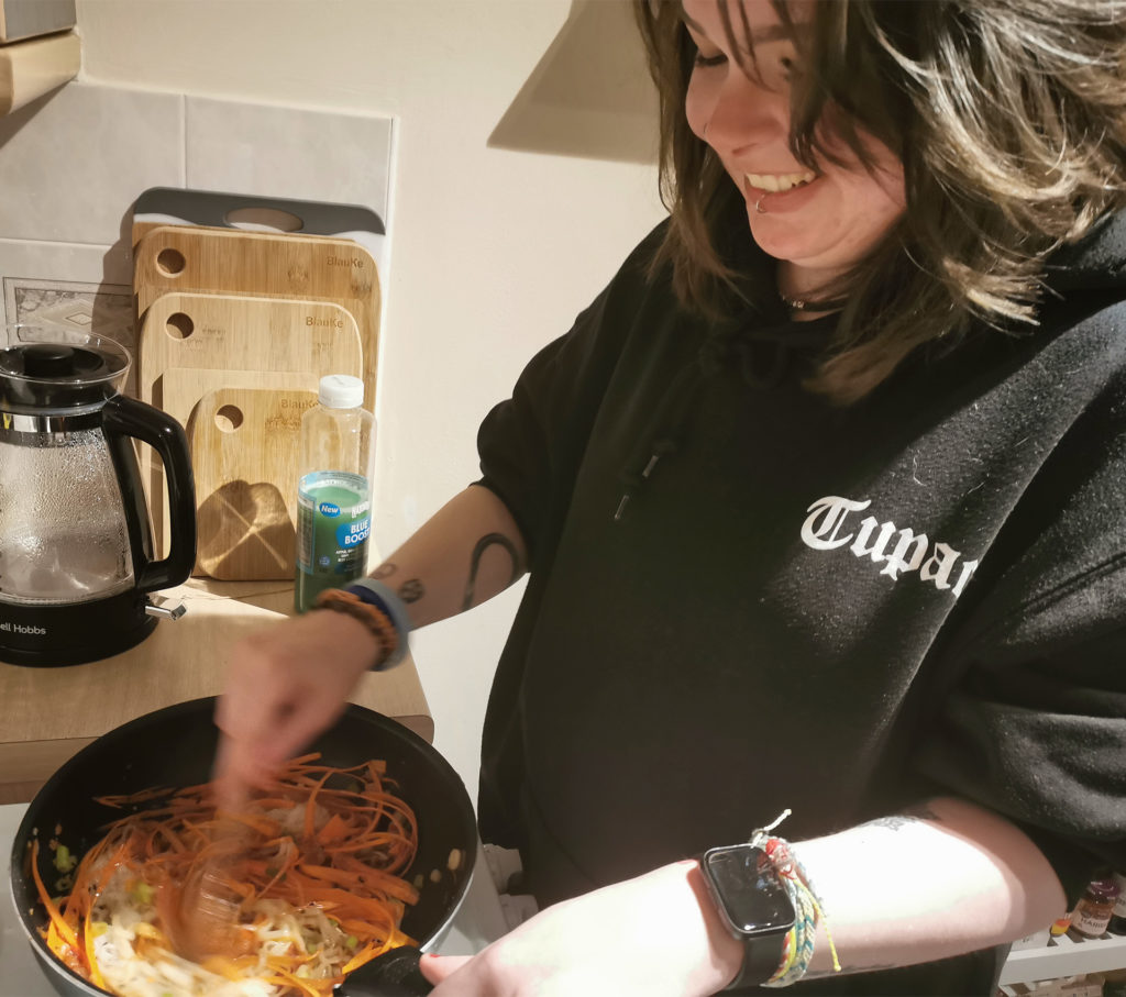 Smiling young woman cooking vietnamese noodle salad with holy moly salsa