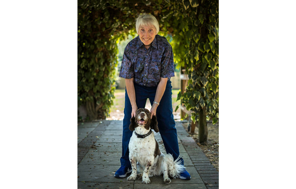 Crime author Joy Ellis, pictured under a yew hedge with a liver and white springer spaniel