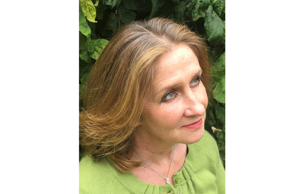 Portrait of crime novel writer Sharon Bolton, high angle, looking off camera, greenery behind