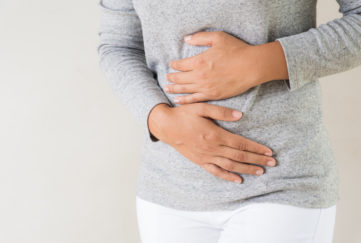 woman with hands over sore stomach