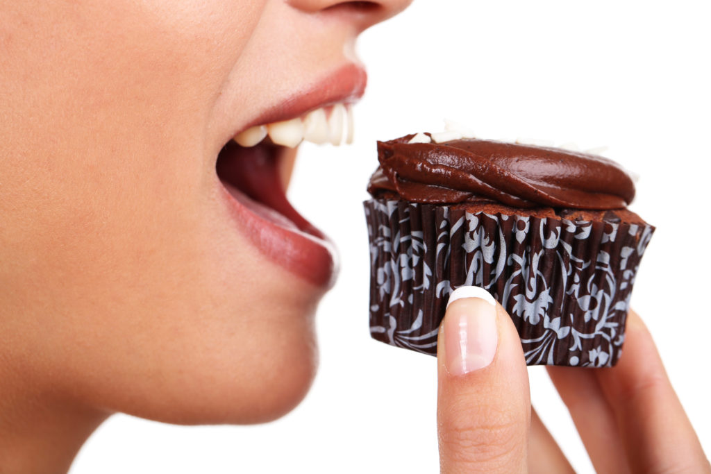 Closeup of woman eating chocolate cupcake; 