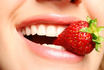 beautiful lips holding a strawberry;