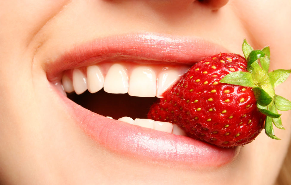 beautiful lips holding a strawberry;
